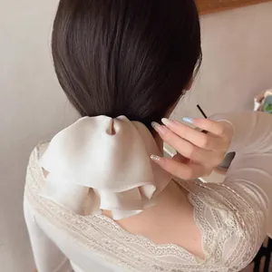 Detail of cream satin oversized double bow hair clip on a low ponytail hairstyle