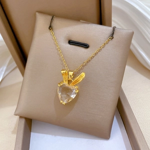 Macro shot of gold rabbit ear pendant with heart-shaped gemstone in beige gift box