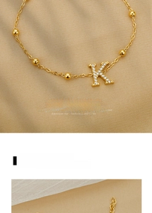 Close-up of golden stainless steel bracelet featuring zircon K-pendant on fabric