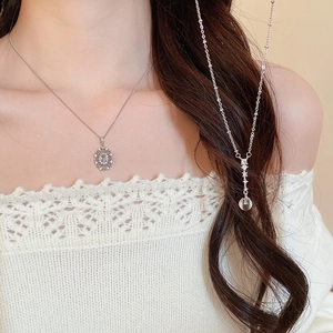 Close-up of elegant zircon oval pendant and daisy necklace on woman neck