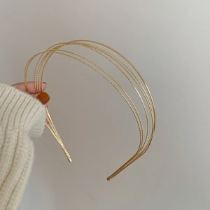 Detail eines minimalistischen mehrlagigen Gold-Haarreifens mit feiner Perlenstruktur