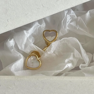 Detail view of heart-shaped gold earring with white shell inlay in jewelry box