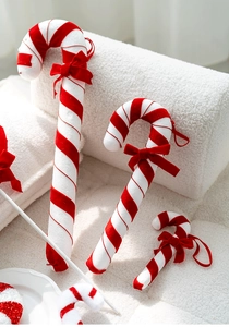 Detail of plush red and white striped Christmas candy cane ornaments with velvet bows