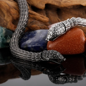 Vintage stainless steel snake bracelet with realistic scales on a rustic wood background