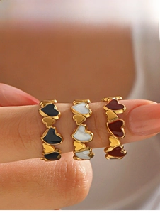 Detail of 18K gold plated heart rings featuring black, pearl white, and red enamel inlays