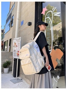 Side view of cream-colored large capacity backpack with multi-pocket utility design