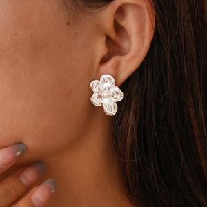 Macro shot of a minimalist silver flower earring with a pearl center on a model