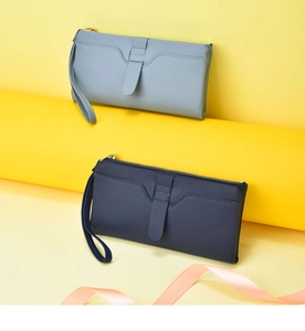 Detail view of stylish women's long wallet with wrist strap in blue and navy color options.