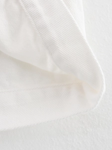 Close-up of white twill denim fabric texture with precision double-stitch sewing details
