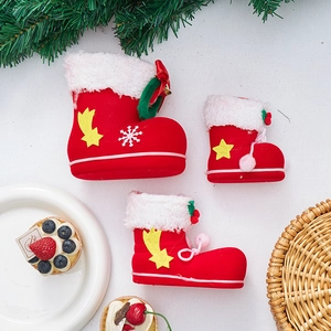 Three red flocked Christmas boot gift containers with white fur trim and bells