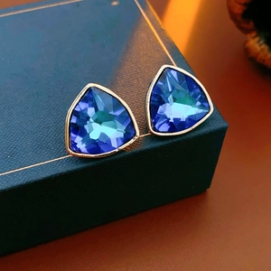 Gros plan de boucles d'oreilles triangles bleues avec bord doré sur une boîte à bijoux