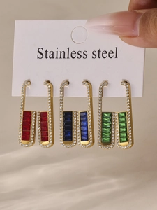 Close-up of stainless steel earrings set with emerald blue and red zircon stones