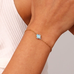 Close-up of 18K gold plated bracelet with oval opal-style stone worn on a female wrist
