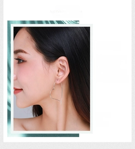 Minimalist silver heart-shaped outline earrings on a model for a modern fashion look