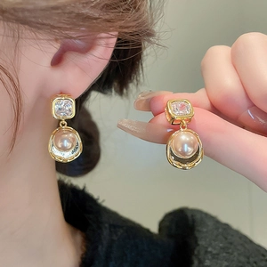 Vintage gold square zircon and pearl drop earrings shown on model and held by hand