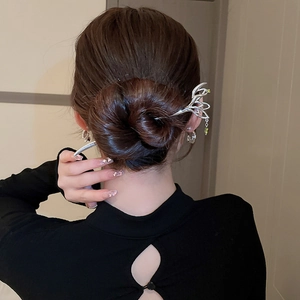 Detailed view of a silver butterfly hair pin with a green gemstone drop in a classic bun