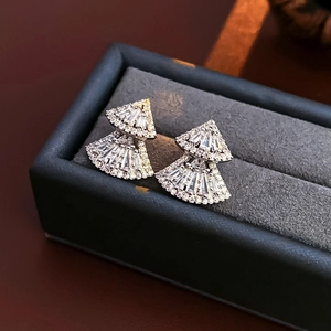 Macro shot of double-layered fan-shaped earrings with zircons in a velvet gift box