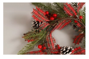 Detail of Christmas wreath with red berries, pine cones and plaid fabric leaves