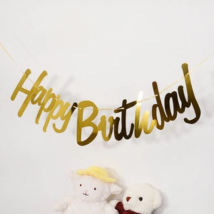 Close-up of golden Happy Birthday party banner hanging on wall with plush animal toys