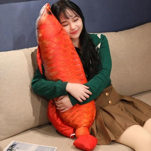Detailed realistic red-orange fish plush pillow with lifelike scale texture on sofa