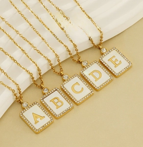 Detailed close-up of square shell letter necklaces with sparkling crystal frames and gold chains
