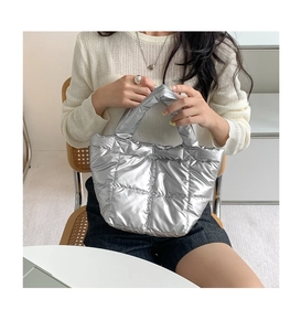 Detail showing the silver quilted down handbag texture and size on a seated model