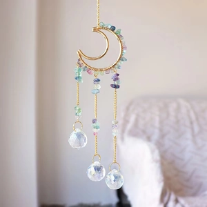 Detailed view of moon-shaped suncatcher with gold wire, crushed stones, and crystal balls