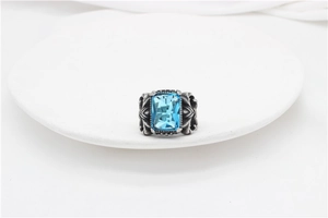 Detailed macro of vintage silver ring featuring square blue gemstone and gothic floral carving