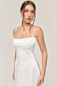 Detail of white satin evening dress featuring delicate lace cutouts and silk-like texture