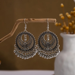 Detail of vintage bohemian silver fringe earrings on natural wooden stand with floral decor