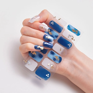 Close-up of laser gold foil nail stickers with dark blue accents and pearl details