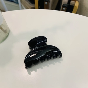 Close-up of black glossy butterfly hair claw clip with smooth finish on white surface
