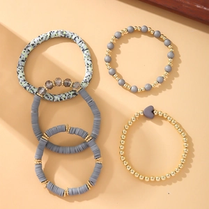Detail of bohemian stretch bracelets with grey clay beads and golden heart charms