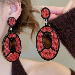 Detail of vintage oval acrylic earrings with red woven texture and amber accent on model