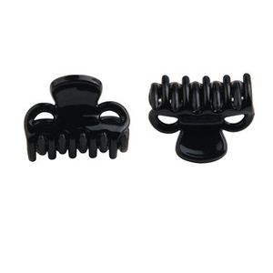 Close-up of small black glossy hair claws with arched teeth and spring mechanism