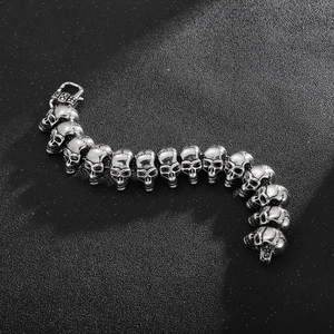 Macro shot of silver stainless steel skull link bracelet with lobster clasp on dark background