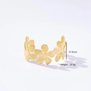 Macro shot of gold floral open cuff bracelet showing brushed metal texture and size