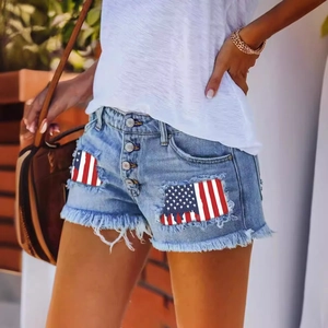 Women's light blue distressed denim shorts with American flag patches and fringed hem