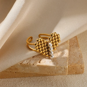 Detail of heart-shaped gold bead ring with white pearls on a minimalist stone base