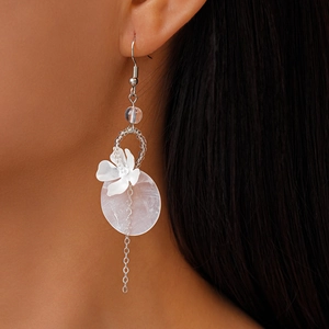 Close-up of bohemian white shell flower earrings with silver tassels on female model