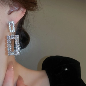 Close-up of model wearing silver geometric hollow earrings with sparkling cubic zirconia
