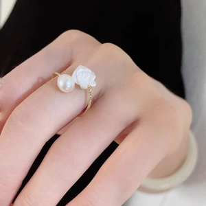 Elegant gold pearl ring featuring white shell rose flower design for women on a model