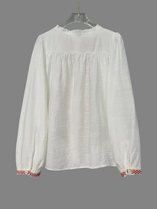 Detail van witte katoenen blouse met etnisch borduurwerk en kraag met ruches