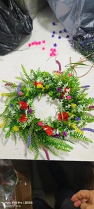 Close-up of vibrant artificial wildflower wreath with colorful ranunculus and green leaves