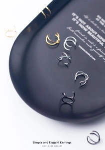 Macro shot of minimalist silver ear clips in gold, silver and black on a tray
