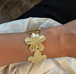 Détail du bracelet manchette en acier titane doré avec trois fleurs et fini brossé