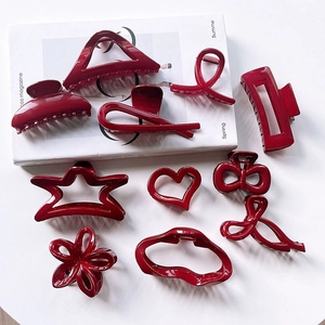 Burgundy hair claw clips in various shapes like stars and hearts on a white magazine