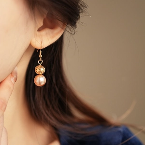 Detailed shot of golden drop earrings with textured pink beads on a female model