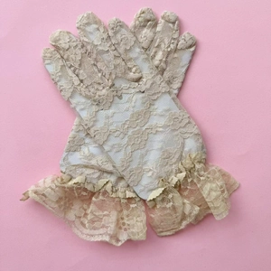 Close-up of beige lace gloves featuring floral patterns and elegant ruffled wrist details