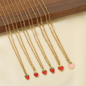 Detail of gold chain necklaces featuring red and pink enamel strawberry pendants